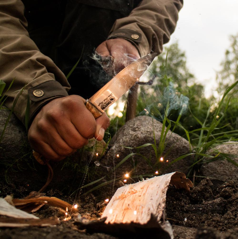 Using a Casström Lars Fält knife to light a campfire with a casström fire steel.