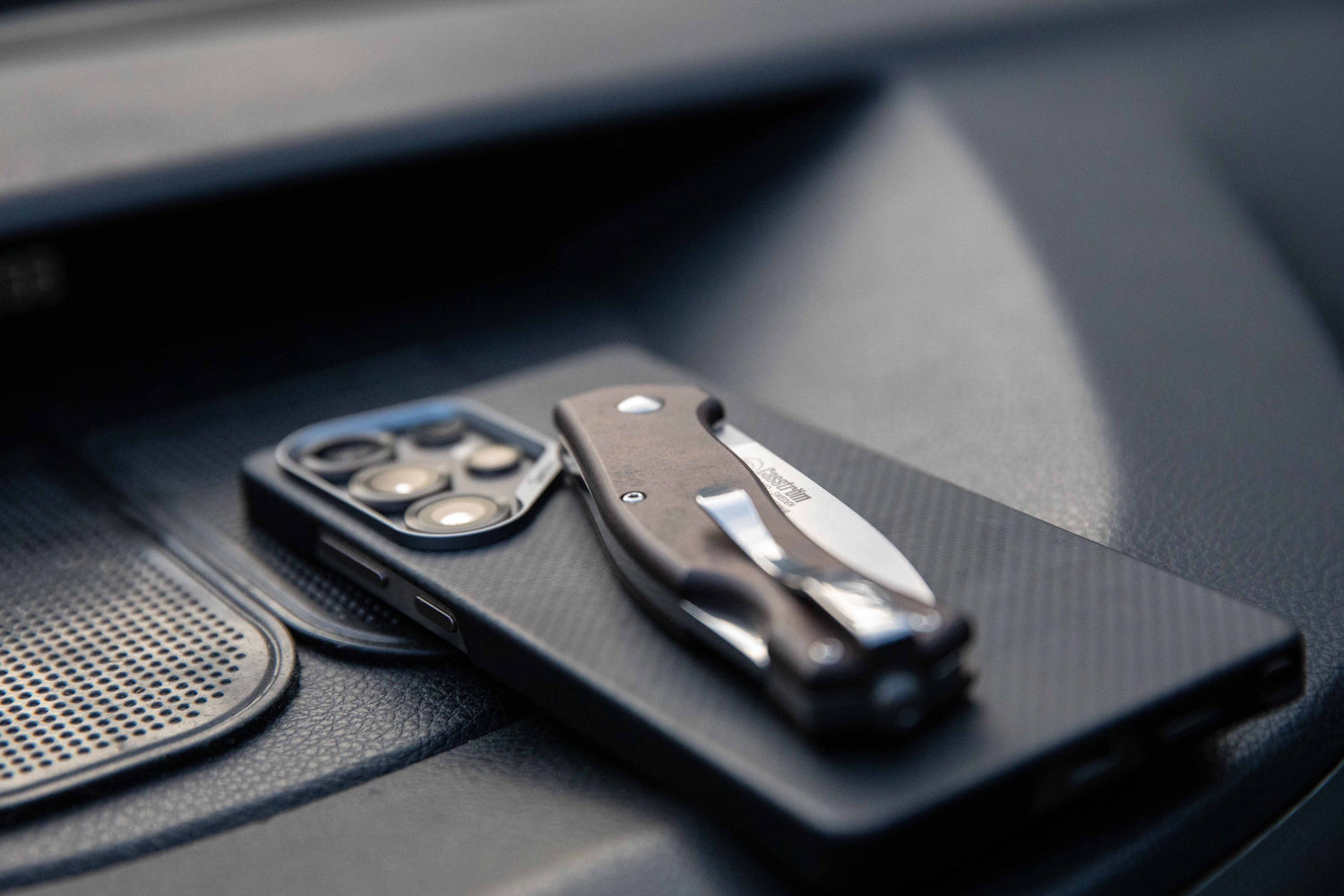 Casström Lars Fält EDC folding knife resting on a mobile phone on a car dashboard.