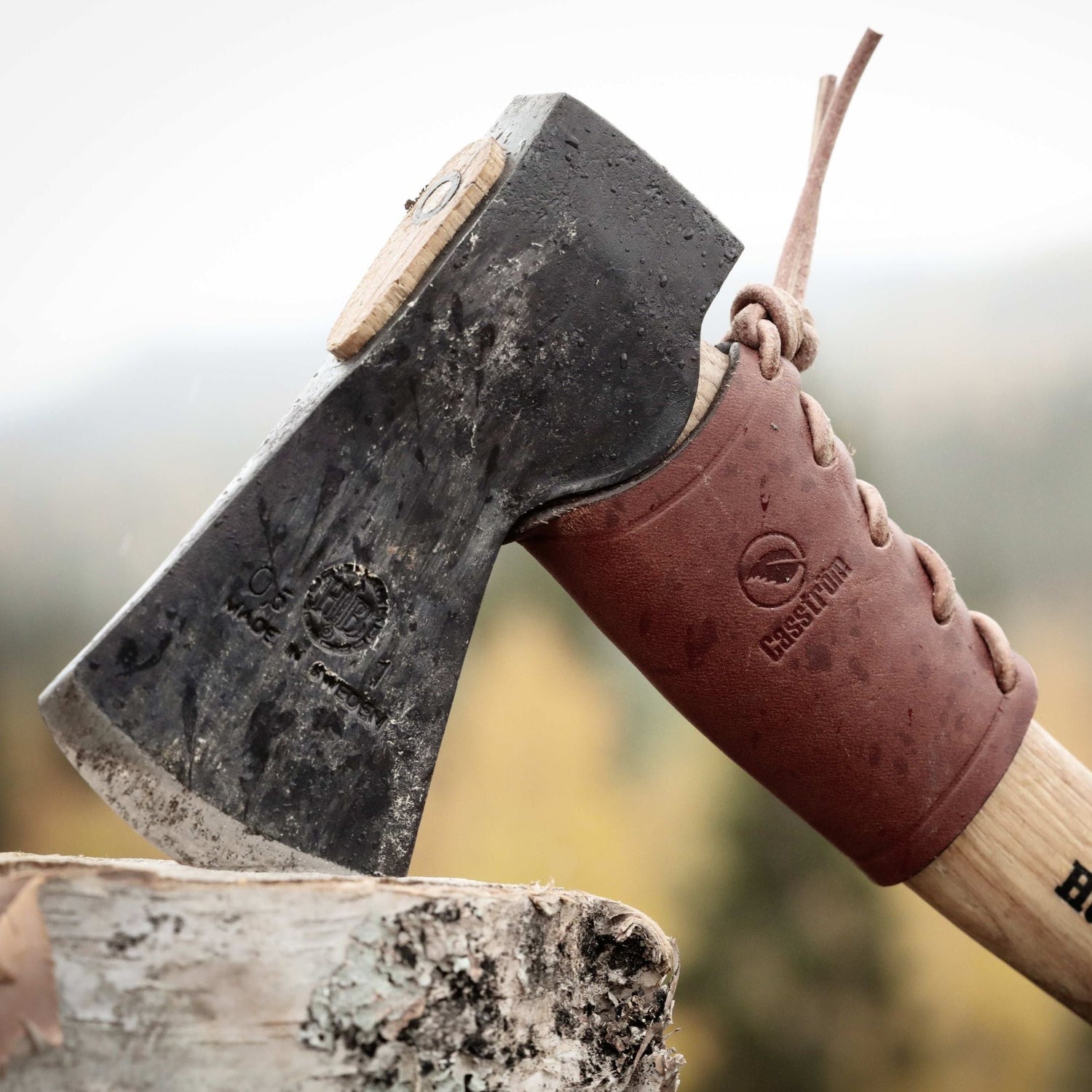 Casström leather overstrike guard fitted to an axe handle during bushcraft and firewood processing outdoors.