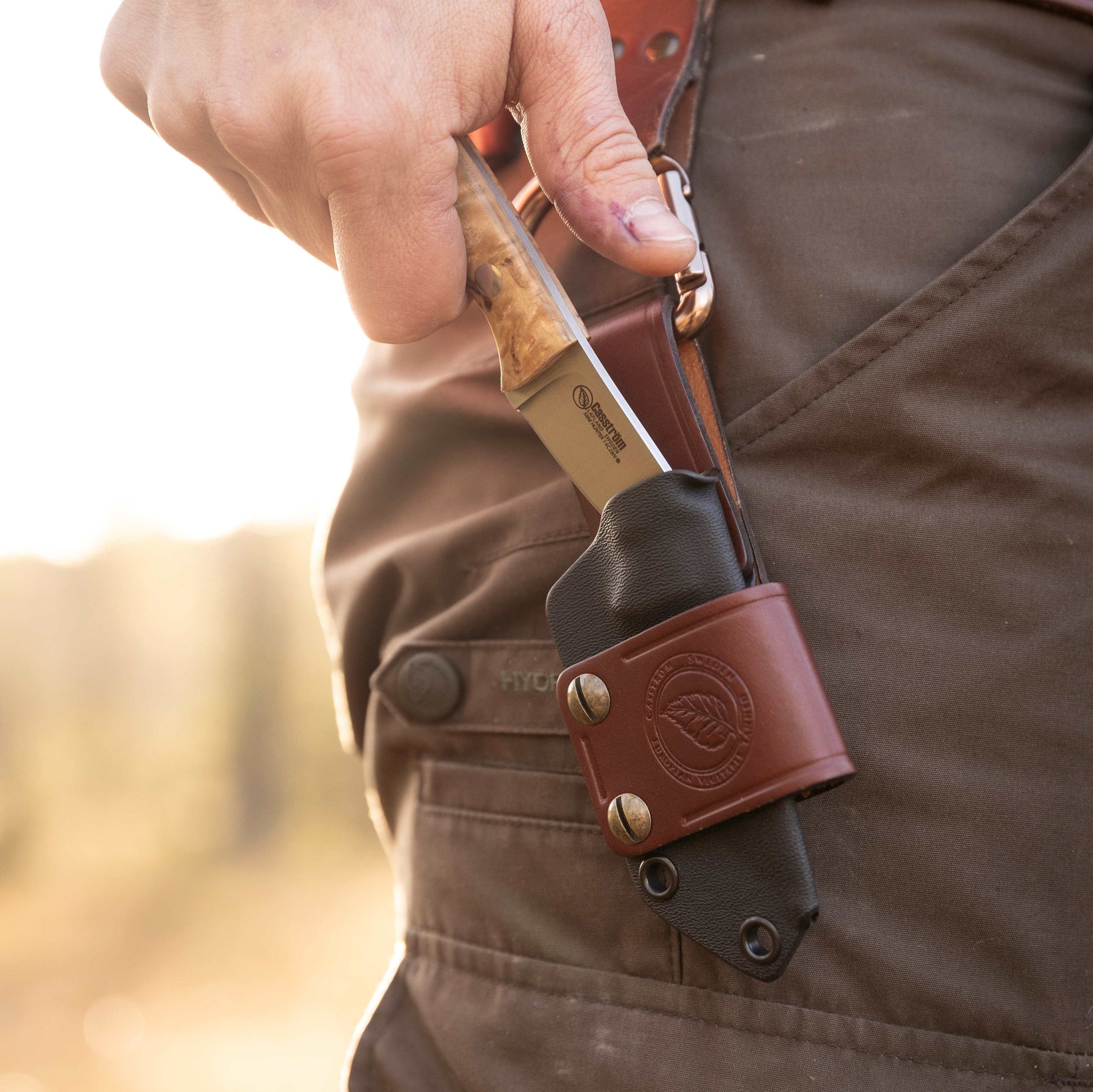 man unsheathing a Casström Safari Mini-Hunter knife from a ydex sheath