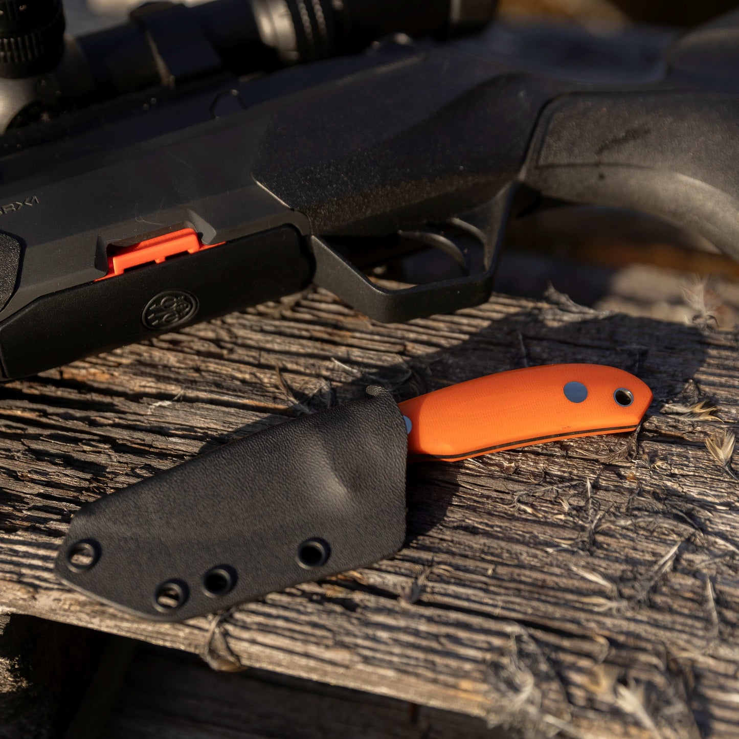 Casström safari Mini-Hunter knife in kydex sheath and next to a hunting rifle.