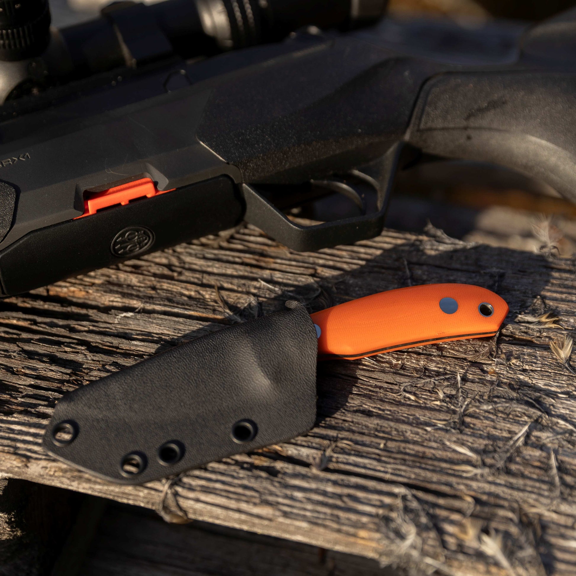 Casström safari Mini-Hunter knife in kydex sheath and next to a hunting rifle.