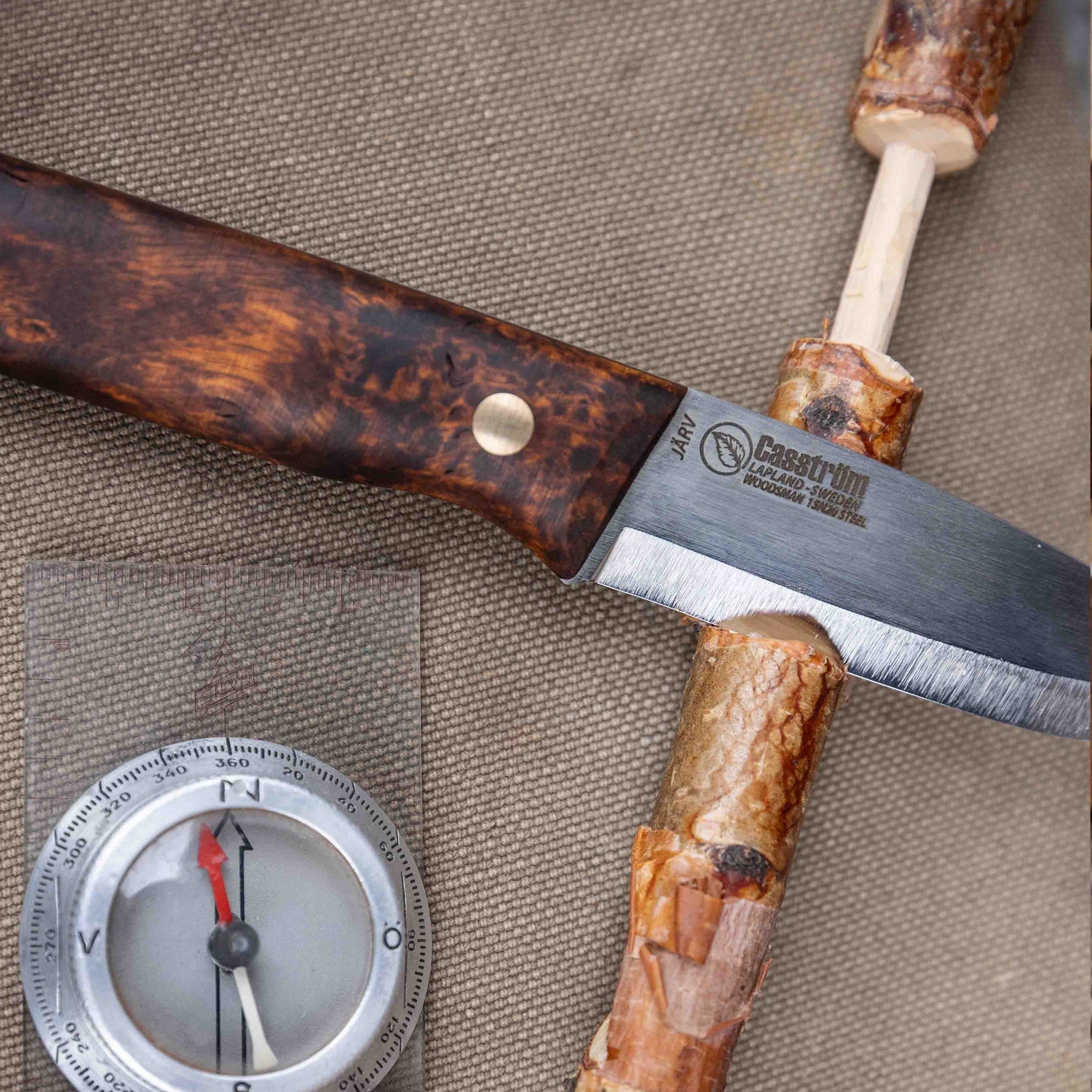 The Casström Woodsman Järv knife, with a carved stick and compass in shot.