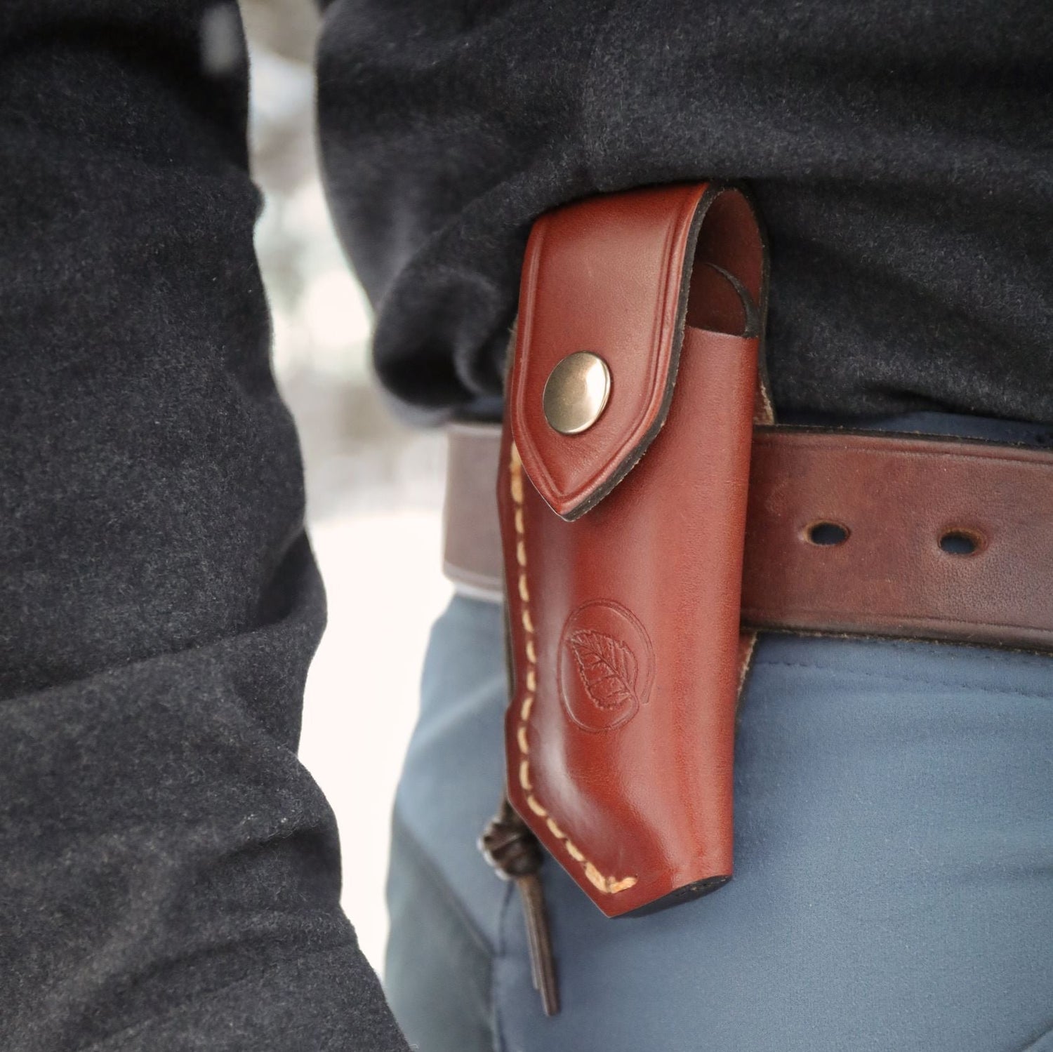 Casström leather folding knife pouch attached to a belt with knife securely stored inside for everyday carry.