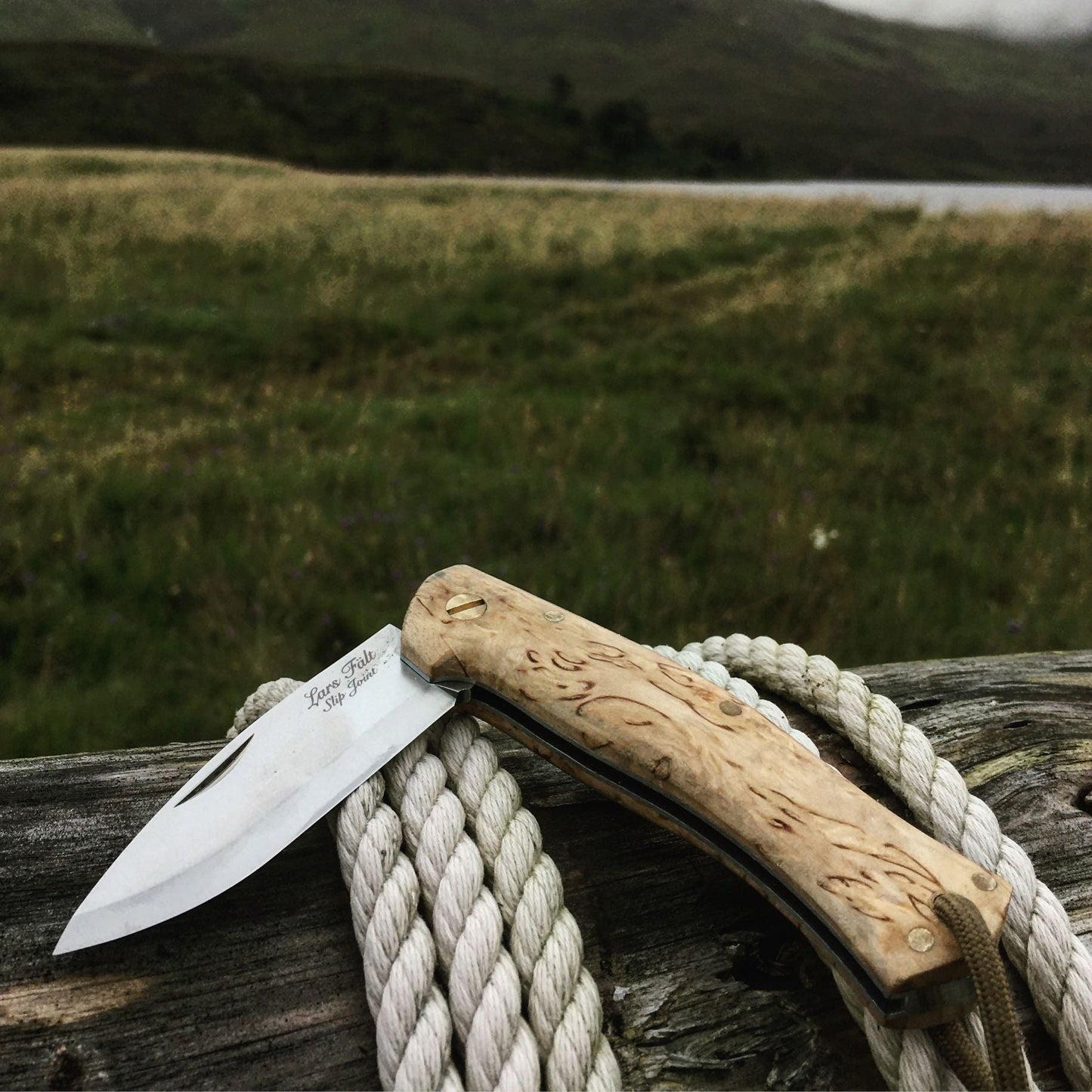 Non-locking Slip Joint pocket knife, made by Casstrom Sweden. Knife is laid on a log in the foreground and has hills in the background