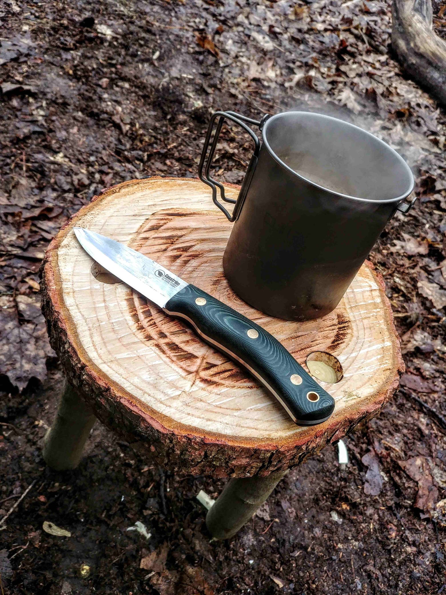 Casstrom No.10 green micarta handle on a wooden stool with a mig of coffee