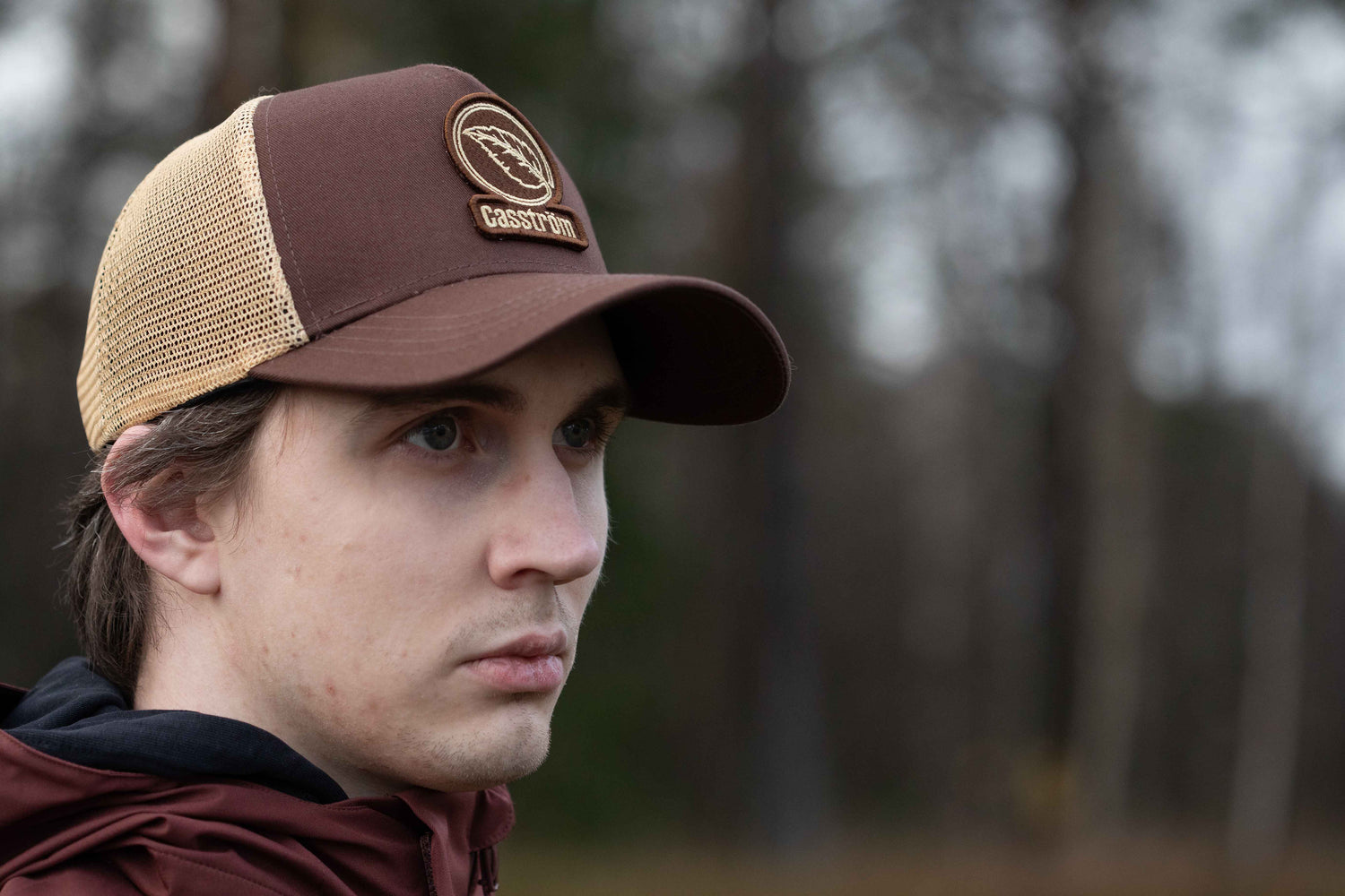 Man wearing the Casström Lapland Trucker Cap outdoors in a Scandinavian forest setting.