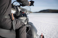 Man sitting on a snowmobile with the Casström Lars Fält knife in canvas micarta on his waist.