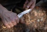 Person holding a Casström No.10 SFK knife with curly birch handle, carving a feather stick.