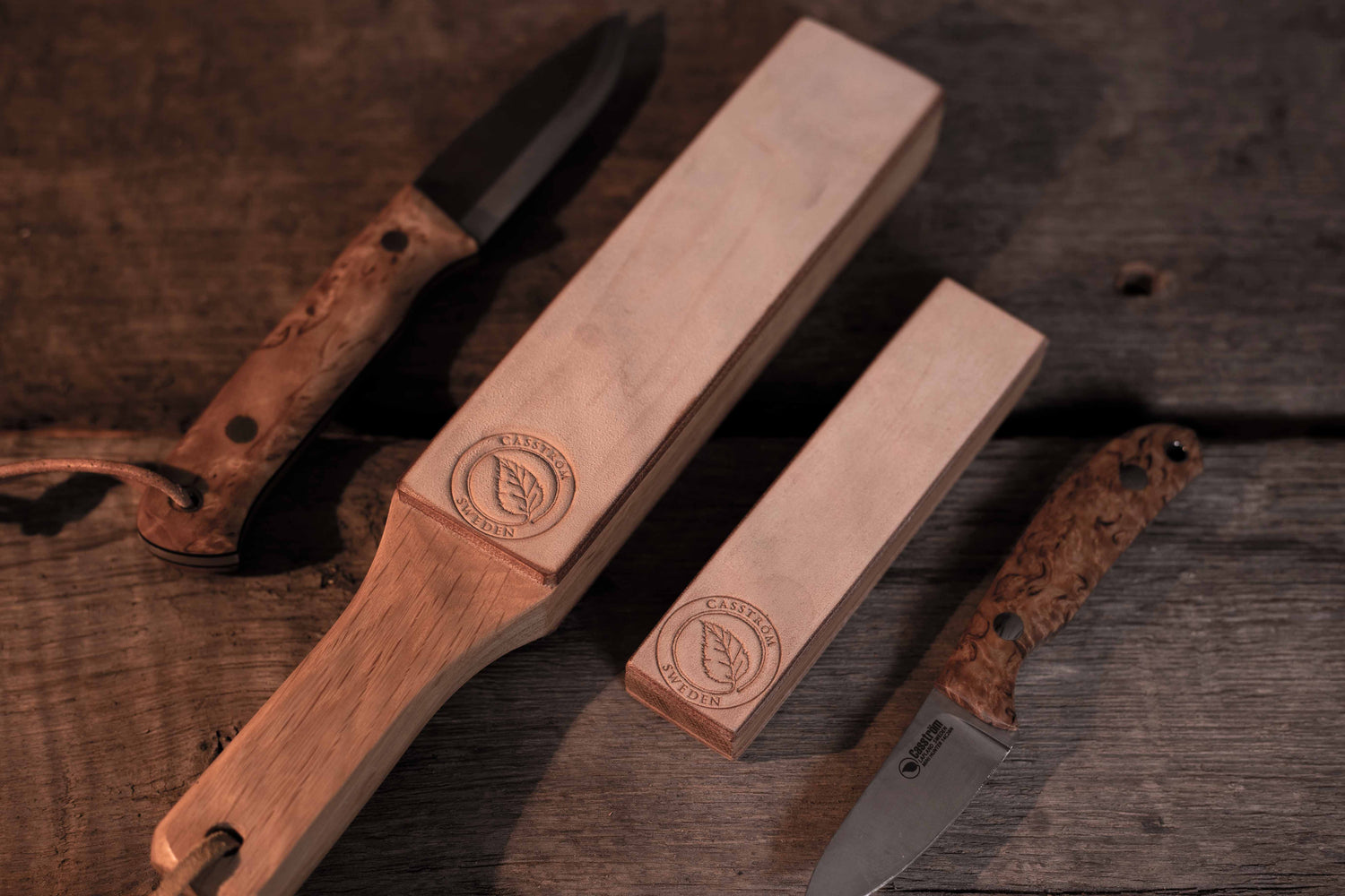 Casström paddle strop, field strop, Woodsman knife, and Safari Mini-Hunter on a wooden table.