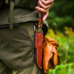A man unsheathing the Casström Lars Fält Järv knife from the leather sheath on his belt.