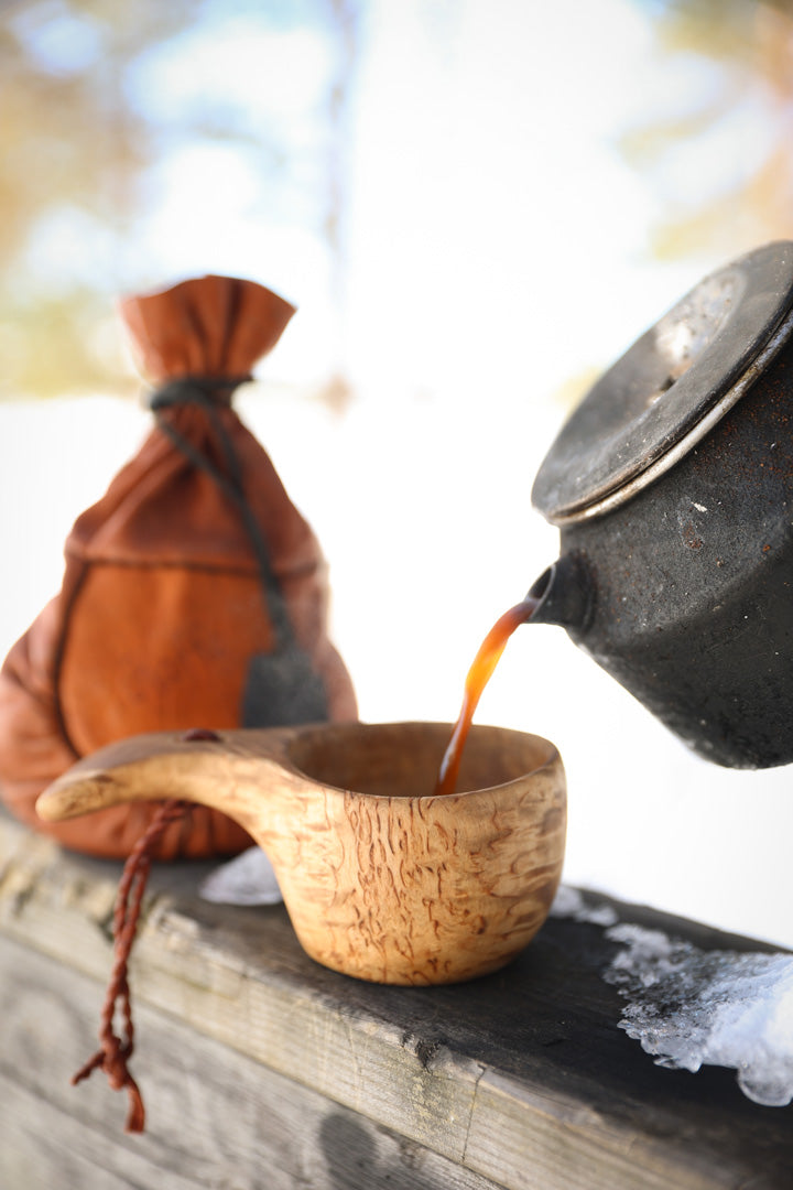 Pouring coffee into a kuksa - a traditional handmade wooden cup from Scandinavia