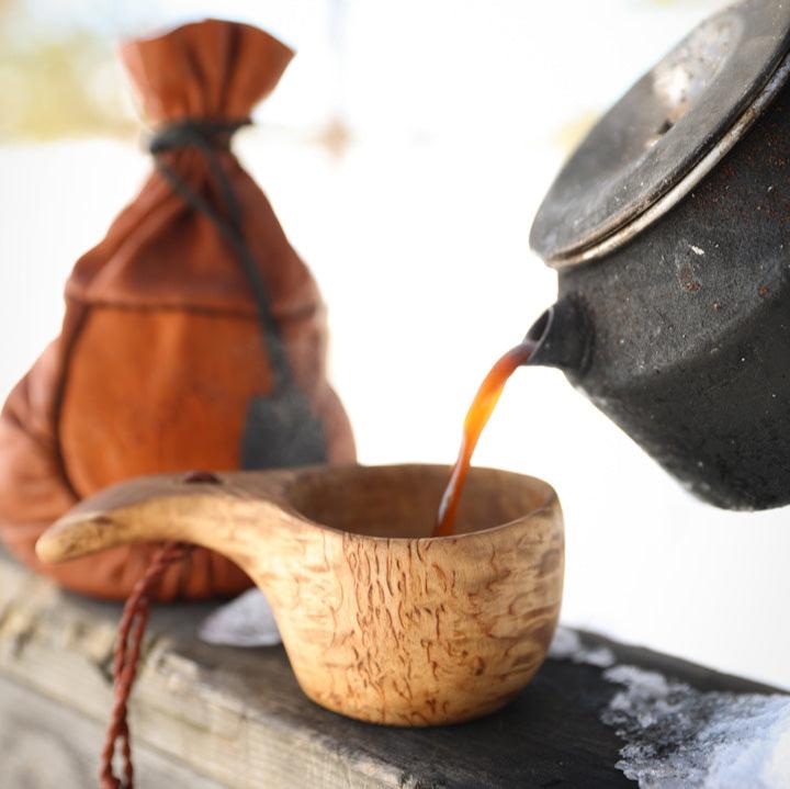 Pouring coffee into a kuksa - a traditional handmade wooden cup from Scandinavia