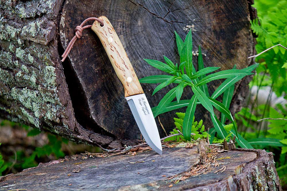 Outdoor shot of the Casstrom Woodsman knife with curly birch handle leaning against a log