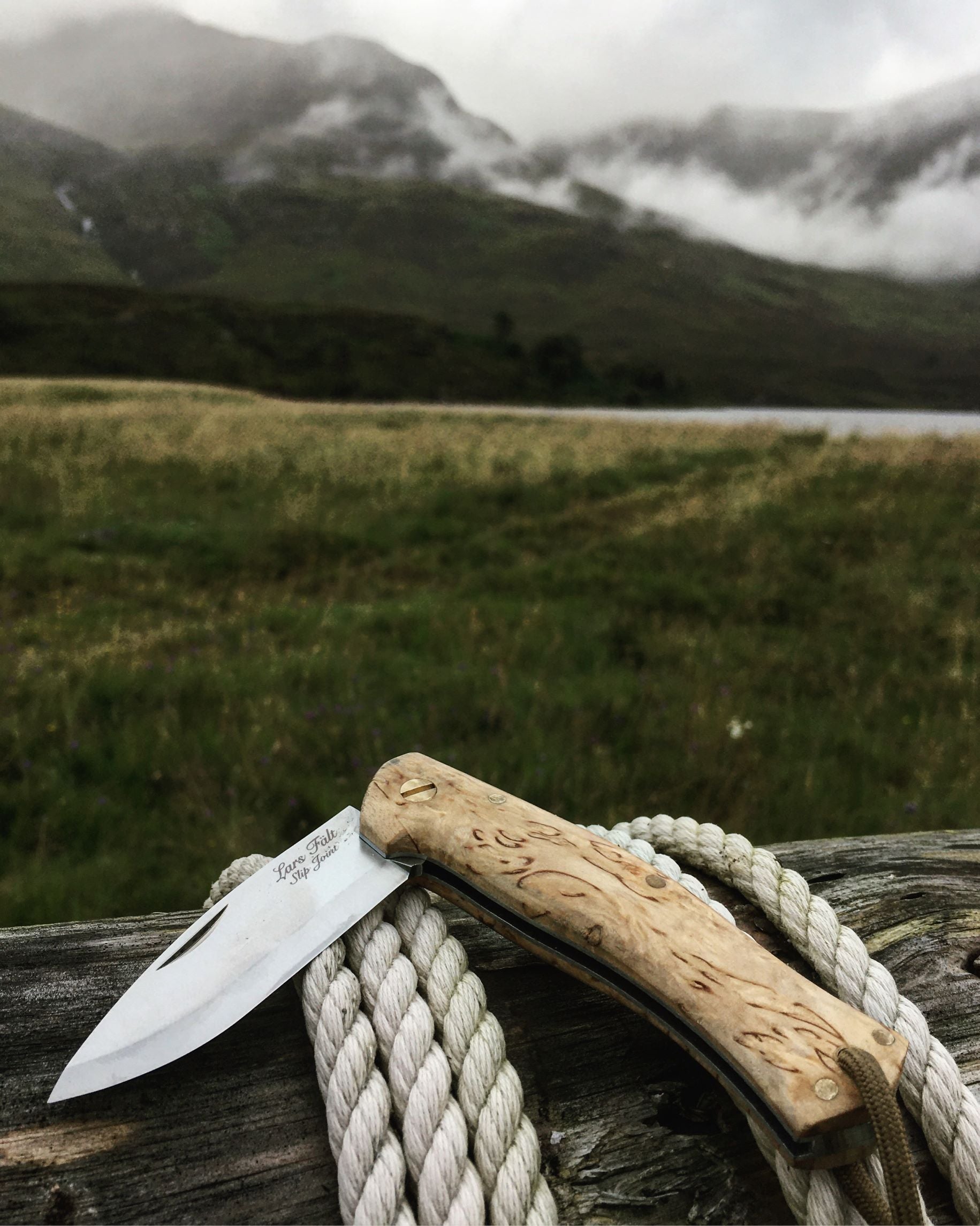 UK-legal Slip Joint folding knife, made by Casstrom Sweden. Knife is laid on a log in the foreground and has hills in the background