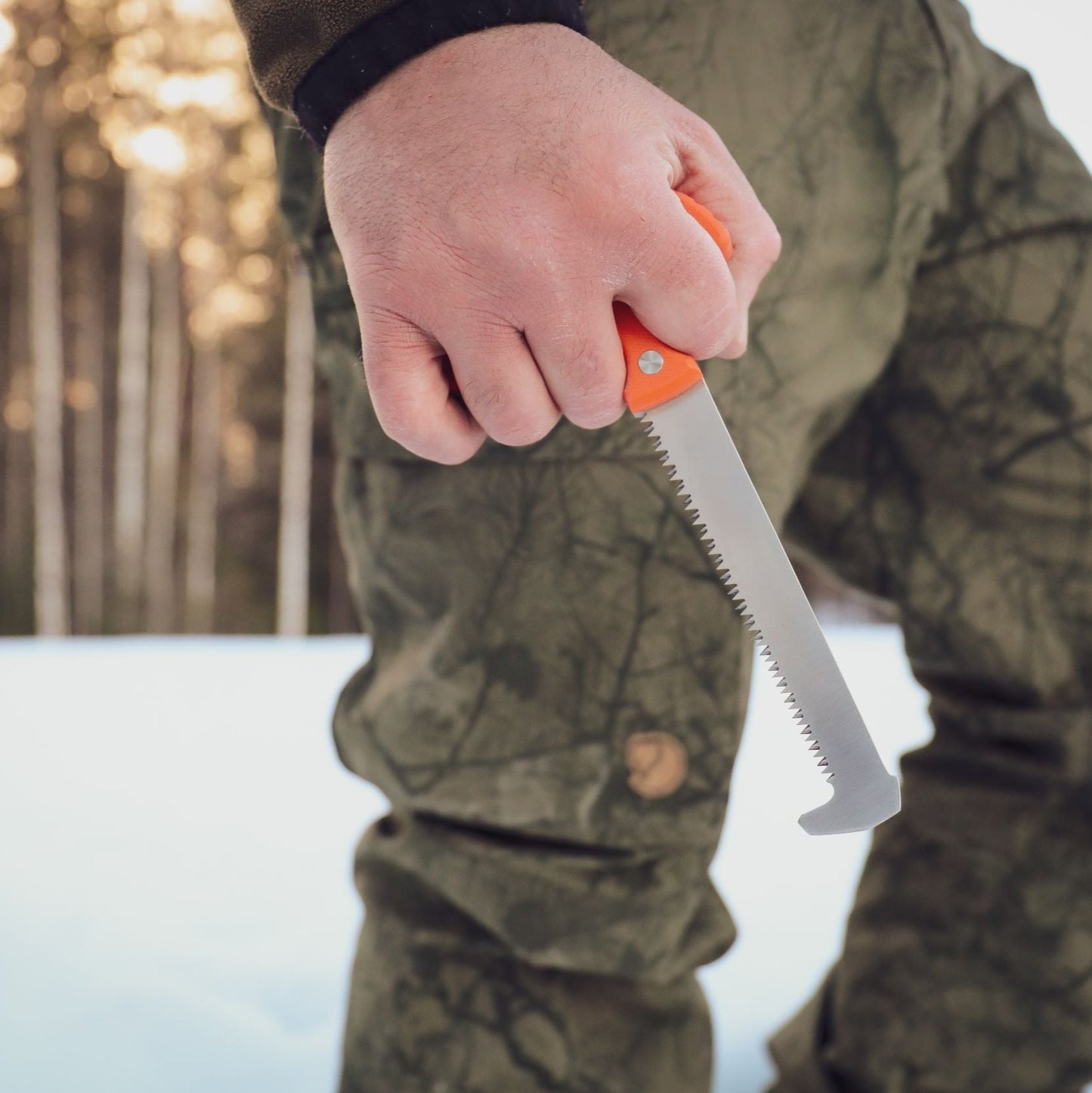 Outdoor shot of a hunter holding the orange handle of the Casström No.11 Bone Saw.