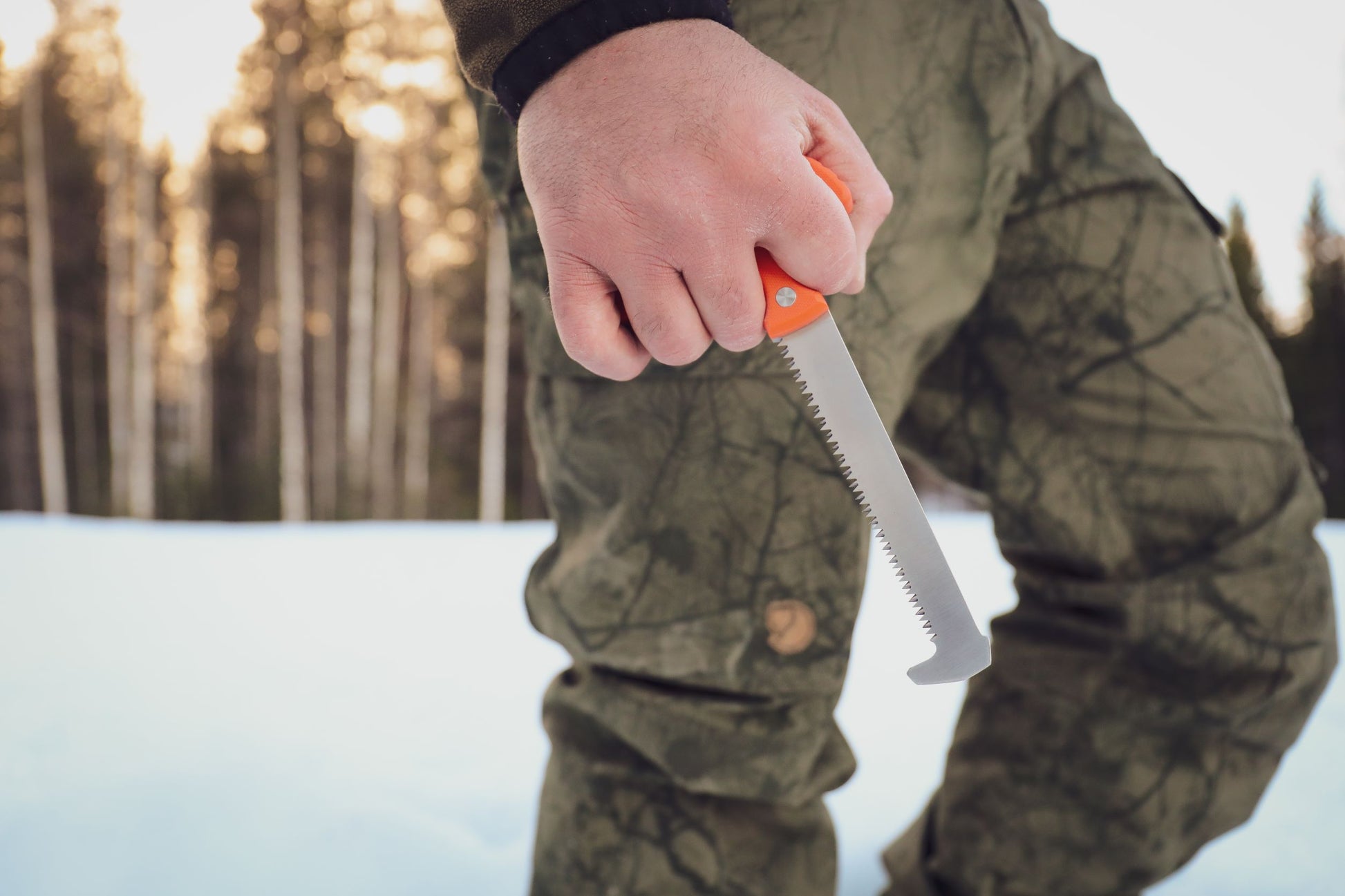 Outdoor shot of a hunter holding the orange handle of the Casström No.11 Bone Saw.