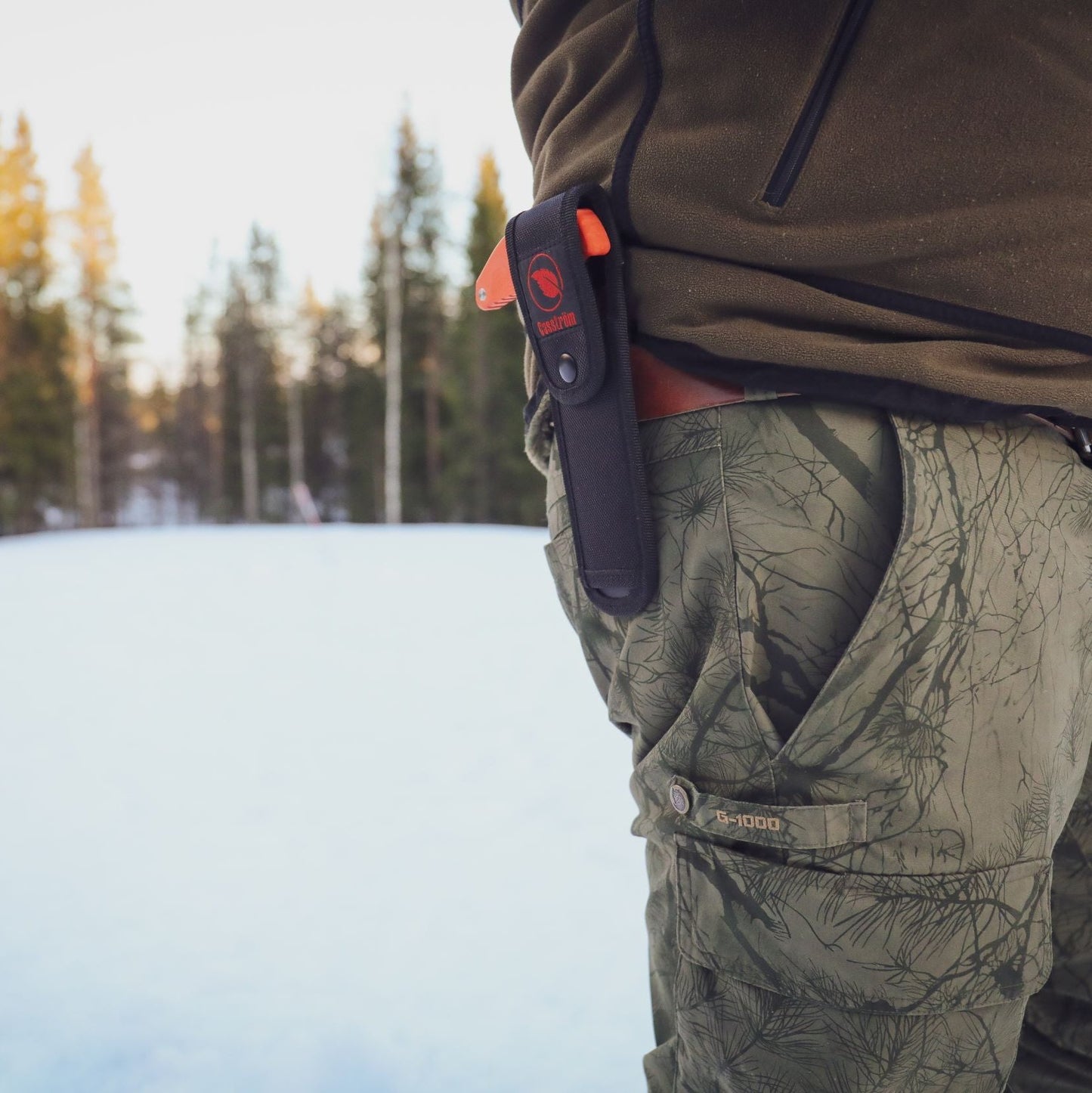 Outdoor shot of a hunter with the Casström No.11 Field Saw in the cordura nylon pouch on his belt.