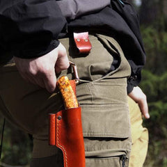 Man unclipping knife sheath from Casström No.3 dangler to safely stow knife in backpack outdoors